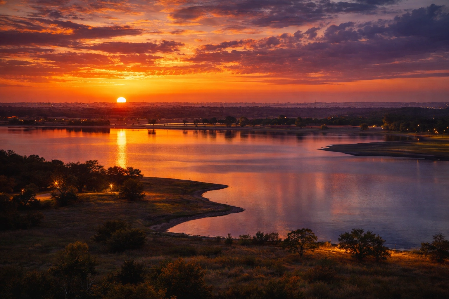 Sunset over Benbrook Lake in Tarrant County Texas with vivid orange and purple skies reflecting on calm water