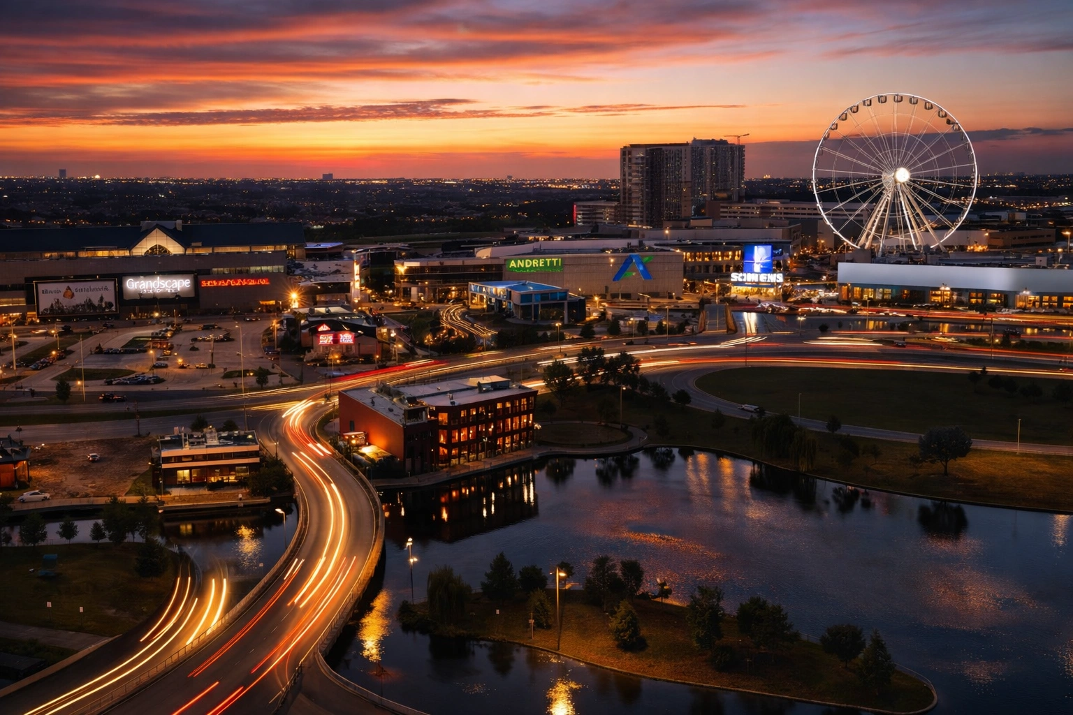 Aerial view of Grandscape mixed-use development in The Colony Texas at sunset with observation wheel, retail centers, and light trails along the roadway